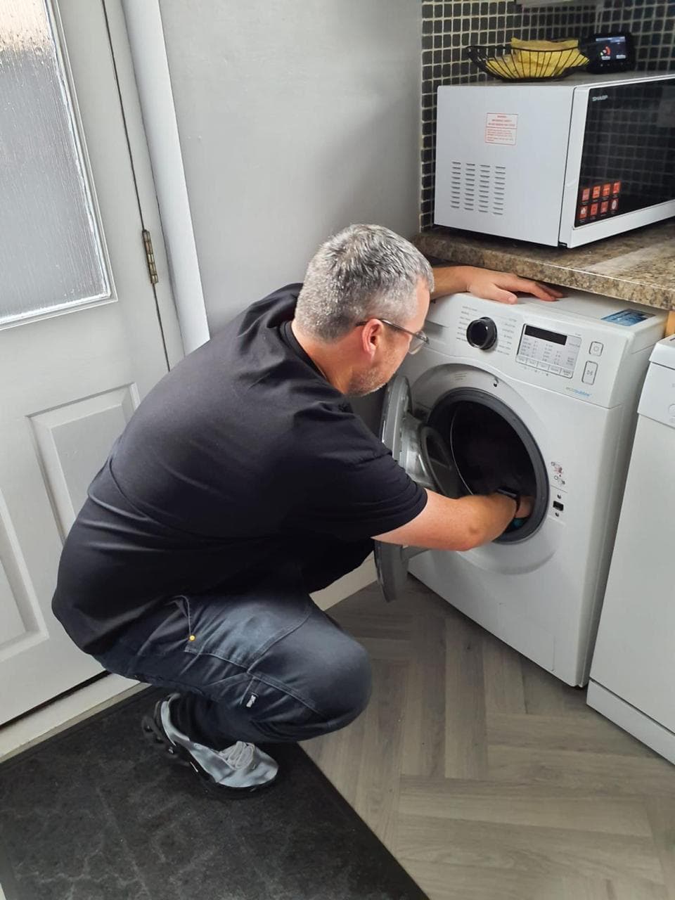 Rob Shields checking a washing machine in a domestic kitchen
